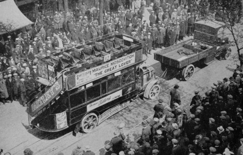 A crowd looks on as an early era London bus,1920