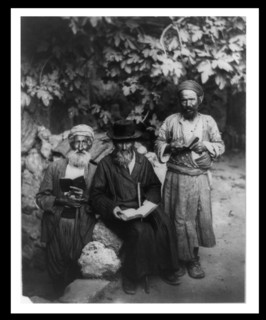 Three elderly men holding books