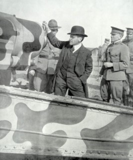 US Secretary of war visits a camouflaged artillery gun in France in WWI.