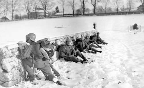 Swiss soldier in the snow peeking over a wall