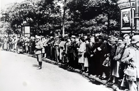 Photograph of crowds gather on the Champs-Élysées in Paris to see German troops enter Paris after the invasion of France in World War Two
