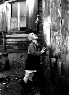 Photograph of a refugee boy drinking from a tap which is the sole source of water for the entire unofficial refugee camp known as Bahnhofstrasse
