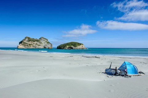 Camping tent on Wharariki Beach with Archway islands in the background