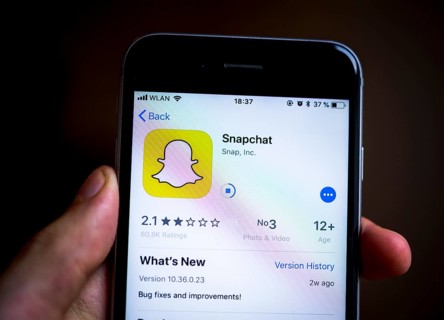 Hand holding iPhone with Snapchat App in the Apple App Store
