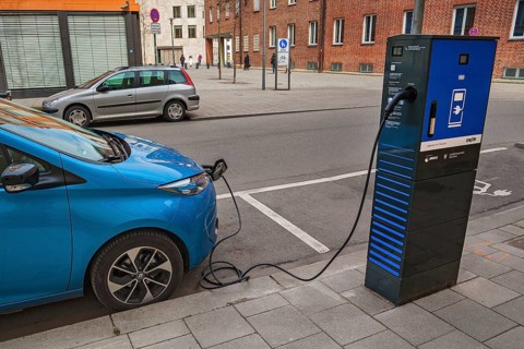 Electric car is charged at green electricity charging station with charging cable