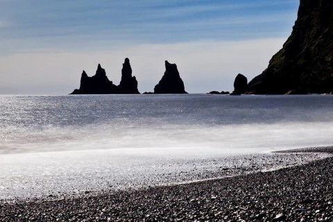 Rock spikes Reynisdrangar with surf on the beach near Vik i Myrdal
