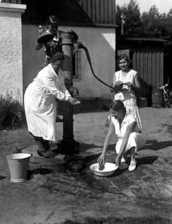 Three women fetching water from a pump