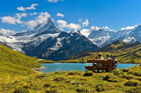 Hikers pausing on a wooden bench at lake Bachalpsee