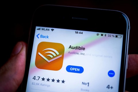 Hand holding an iPhone displaying the Audible app