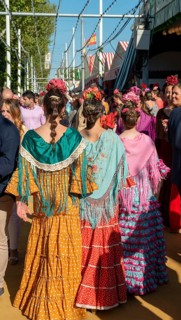 Spanish women with colorful flamenco dresses in front of marquees