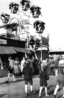 People walk over the fairground and look at the ferris wheel