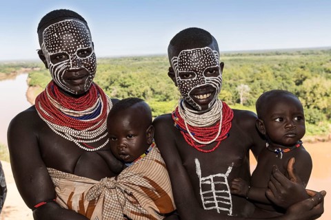 Two young women with babies and face painting
