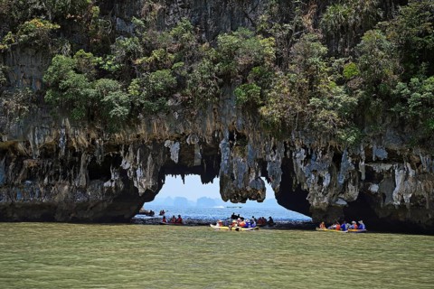 Tourists exploring eroded limestone rocks with canoes in Phang Nga Bay