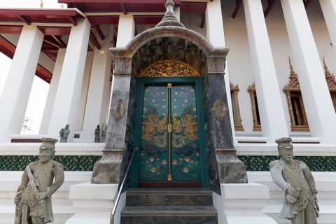 Painted door and stone figures in front of the Ubosot