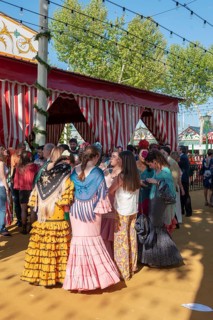 Spanish women with colorful flamenco dresses in front of marquees