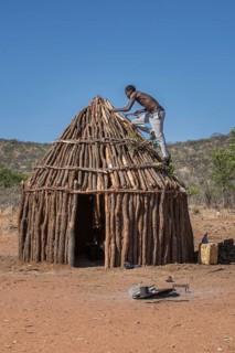 Man of the people of Ovahimba or Himba builds on the roof of a wooden hut