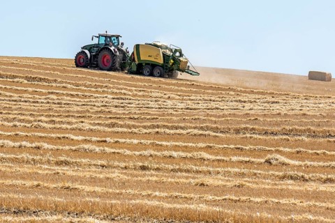 Tractor with straw baler on a mown wheat field