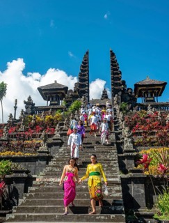 Balinese believers in traditional clothing go down stairs