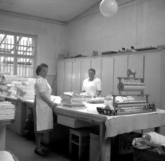 Women folding fabrics around 1950