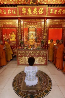 Buddhist Sacrifice Ceremony with praying monks and kneeling woman