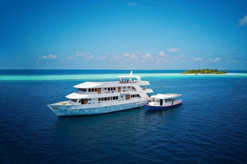 Diving safari ship MS Keana with diving dhoni anchored off an uninhabited palm island