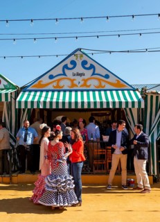 Spanish women with colorful flamenco dresses in front of marquees