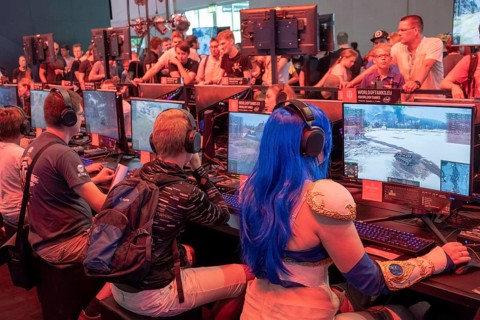 Female visitor in cosplay costume sitting in front of a military computer game