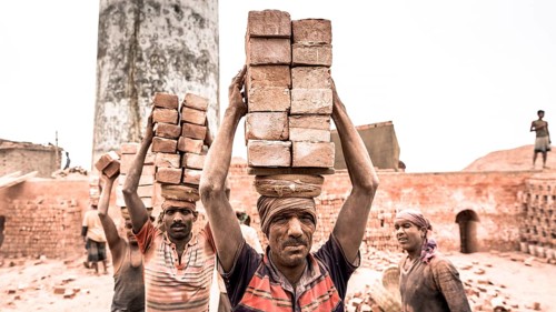 Workers with bricks on their heads in the brickyard
