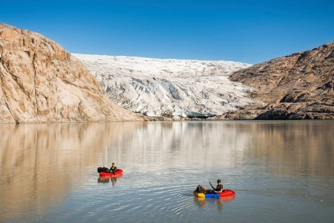 Two persons with pack rafts on fjord