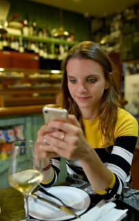 Young woman looks at her mobile phone in Tapas Bar