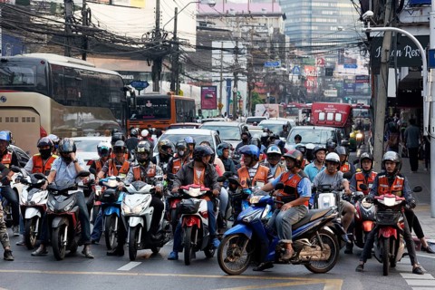 Many moped drivers are waiting at an intersection