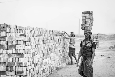 Workers with bricks on their heads in the brickyard