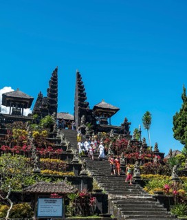 Balinese believers in traditional clothing go down stairs