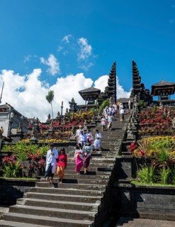 Balinese believers in traditional clothing go down stairs