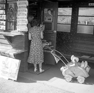 Woman with pram looks after newspapers