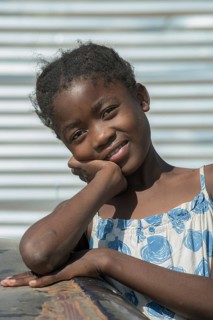 A girl is playing a car wreck in the slum district