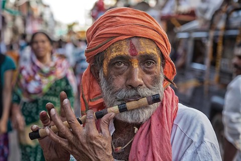 Sadhu plays flute at hinduistic festival Kumbh Mela