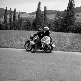 Man and daughter riding a motorbike on a country road
