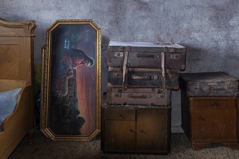 Old suitcases and picture of saint in an attic