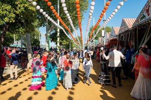 Spanish women with colorful flamenco dresses in front of marquees
