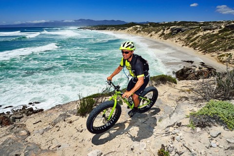 Mountainbiker with Fatbike on cliff