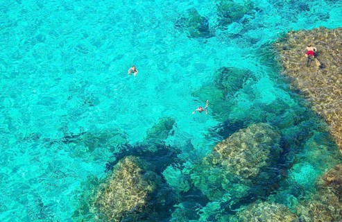 People swimming in the emerald waters of Cala Mitjana
