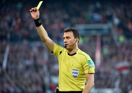 Referee Felix Zwayer gesticulates and shows yellow card as warning