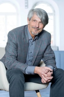 Man sits smiling in an armchair