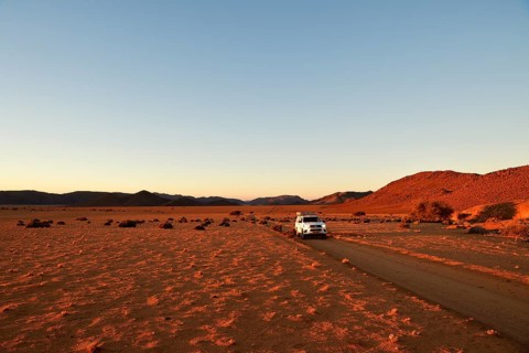 All-terrain vehicle drives on sandtrack in the evening light