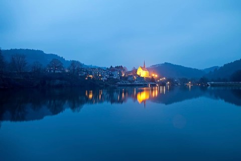 Beyenburg reservoir with the illuminated church of St. Mary Magdalene in the evening