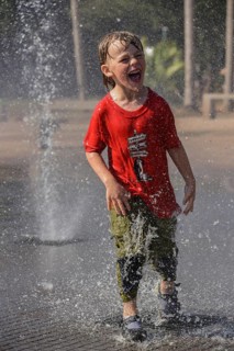 Boy stands in a fountain and gets sprayed