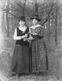 Two women with hat share a beer in the forest