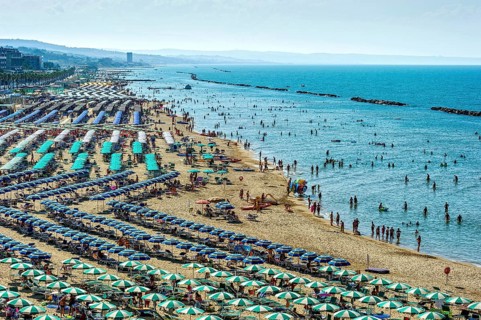 Overcrowded touristic bathing beach with umbrellas