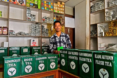 Tea merchant behind large tins with tea in his shop